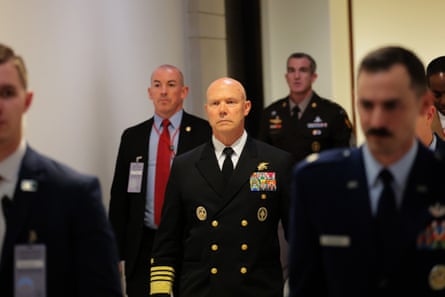 A man in navy uniform walking down a corridor