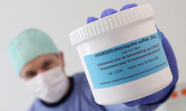 A pharmacist displays a box of hydroxychloroquine