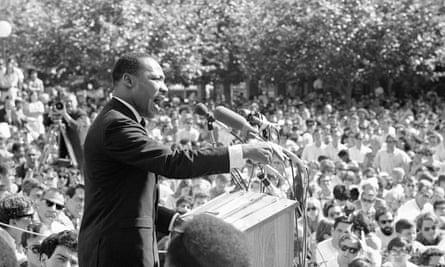 Black and white photo of Black man speaking and gesturing behind lectern to sea of mostly white face.