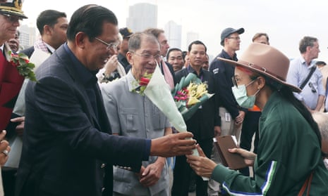 Cambodia’s Prime Minister Hun Sen, left, gives a bouquet of flowers to a passenger who disembarked from the MS Westerdam.
