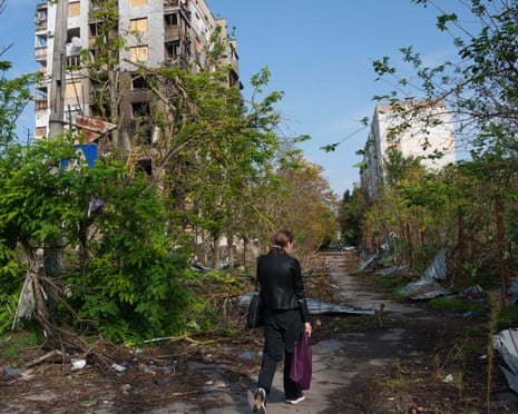 A woman walks in front of a residential building damaged in a Russian attack during a local ceasefire related to a humanitarian aid mission in Russian-occupied Oleshky in Kherson, southern Ukraine