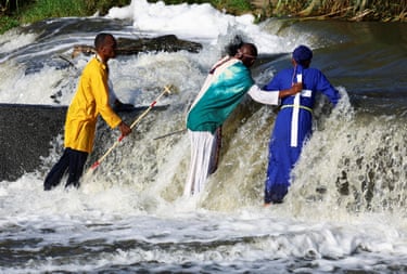 Image 18: Three Christians conduct a baptism in a fast-flowing river