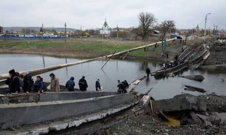 People leave and return to their shelters as they cross a destroyed bridge in order to collect aid in the eastern Donbas region of Bakhmut, Ukraine, 30 October.