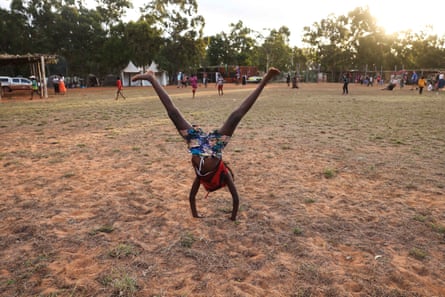 Child doing a handstand on a patchy field