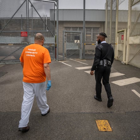 An officer and an inmate walk through an outside section of a prison