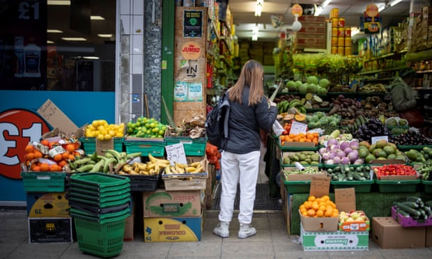 A customer shops for fruit and vegetables at a greengrocer's shop in Walthamstow, east London