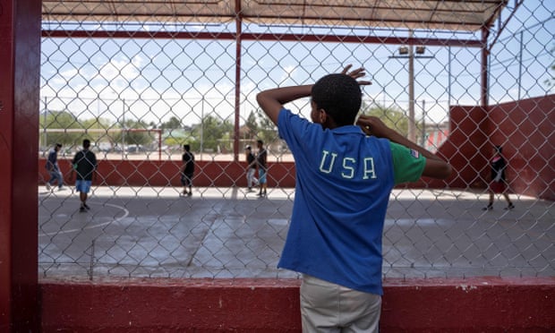 A resident of a migrant shelter watches a soccer match at a nearby park on 9 June.