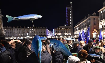 Sardine signs are held in the air at the Turin protest.