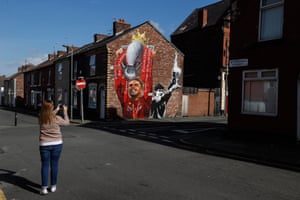 A fan photographs a Jordan Henderson mural outside Anfield.
