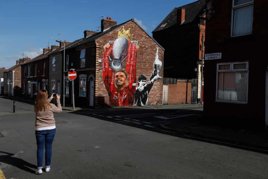 A fan photographs a Jordan Henderson mural outside Anfield.