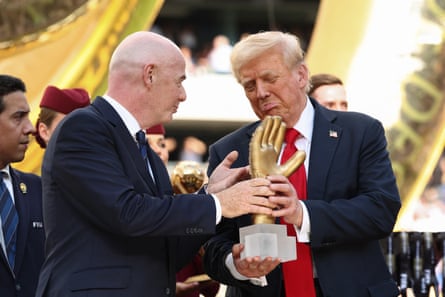 Donald Trump looks at a golden glove trophy next to Gianni Infantino