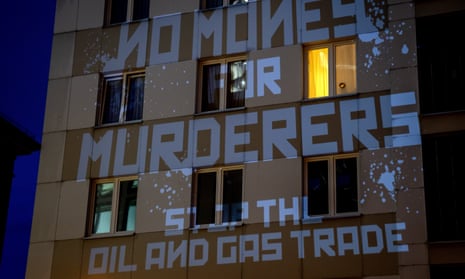 The words ‘No money for murderers' and 'stop the oil and gas trade’ are projected onto a building