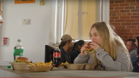 A young woman eats a hamburger in a restaurant.