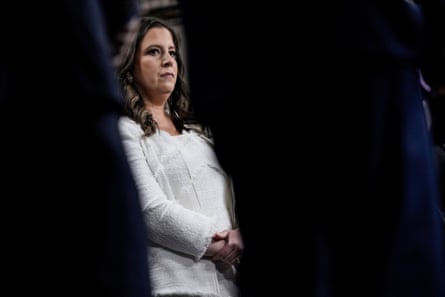 A woman in a white suit stands at a press conference