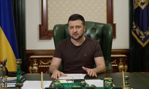 President Voldymyr Zelenskiy at his desk in a military issue T-shirt.