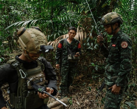 Three soldiers from rebel groups in helmets and uniform with guns in the jungle