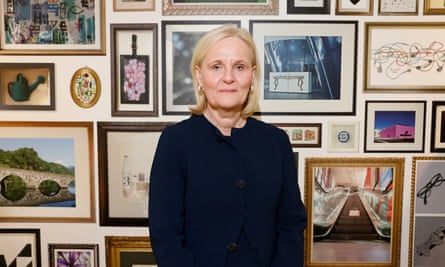 Amanda Blanc poses for a picture in front of a wall full of photos in frames