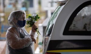 Un familiar de una víctima del coronavirus sostiene flores junto a un coche fúnebre en el cementerio Nossa Senhora Aparecida en Manaus, estado de Amazonas, Brasil, el 13 de enero de 2021.