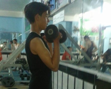 A young boy lifts a weight in a gym.