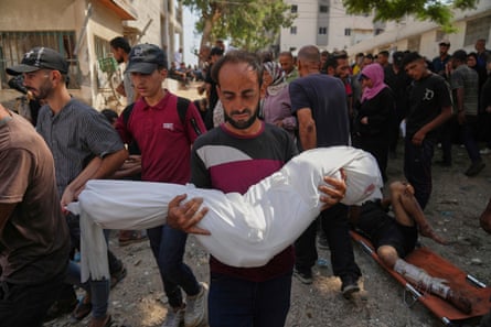 A Palestinian man carries the body of his 7-year-old nephew, Alaa Al-Toum, who was killed in an Israeli airstrike on Friday night, during his funeral at Shifa hospital in Gaza City Saturday.
