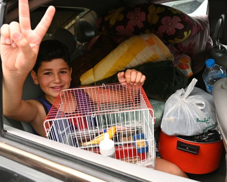 A child holding his pet bird makes a victory sign from the backseat of a car loaded with belongings as residents flee their homes, after Israel once again ordered attacks on the southern suburbs of Lebanon's capital Beirut.