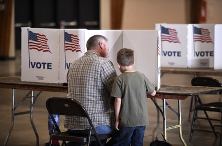 A Nevada county voter sits down with his son next to him to fill out his ballot at the Nevada county fairgrounds in Grass Valley, California.