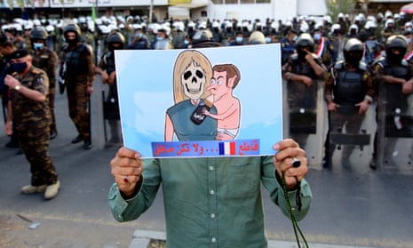 An Iraqi man carries a caricature depicting Emmanuel Macron and his wife Brigitte during a protest in front of the French embassy in Baghdad