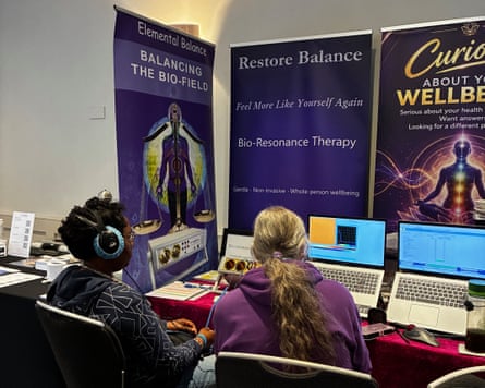 Two people sitting in front of wellness banner stands and laptops