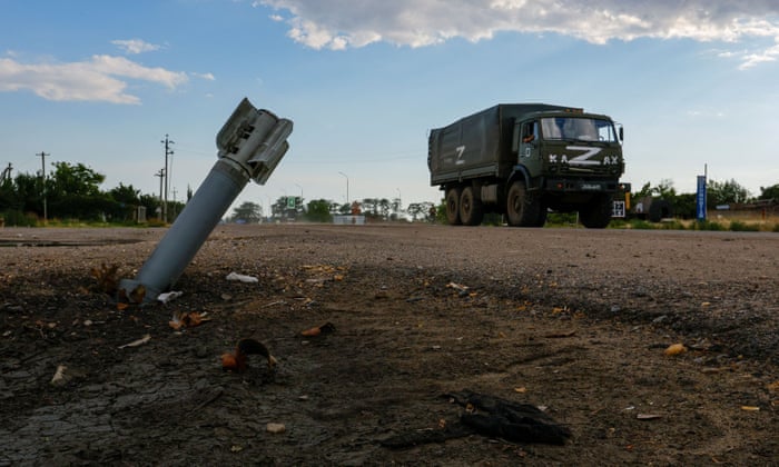 A Russian military truck drives past an unexploded munition in the Russian-controlled village of Chornobaivka in the Kherson region