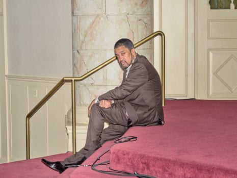 man in a suit sitting on red-carpeted stairs