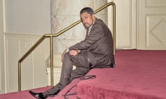 man in a suit sitting on red-carpeted stairs