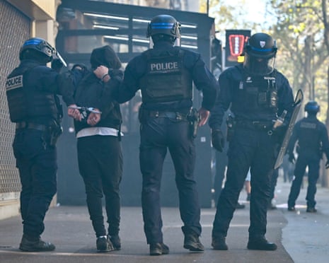A protester is detained by riot police officers during clashes near the Place de la Bastille in Paris.