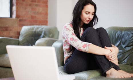 Woman sitting on sofa with her laptop nearby