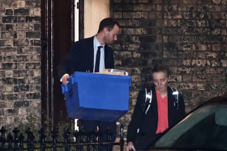 A police officer leaves a London property linked to Mandelson carrying a box.