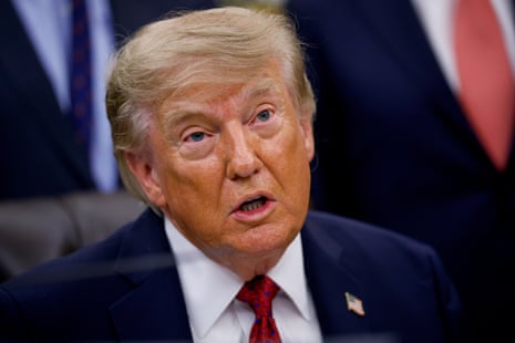 President Trump, in a dark suit and red tie, speaks during an Oval Office event