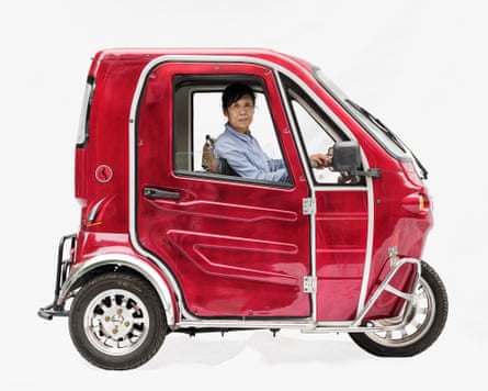 Taxi driver Ahong in a Xinfu in Shanghai, China. It is a very small red bubble-shaped car with three wheels