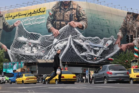 Vehicles drive past a billboard in Tehran reading: ‘The strait of Hormuz remains closed.’