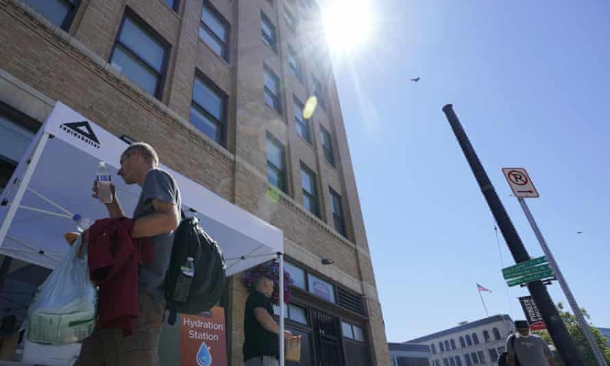 A person walks away after being given bottles of water at a hydration station in front of the Union Gospel Mission in Seattle.