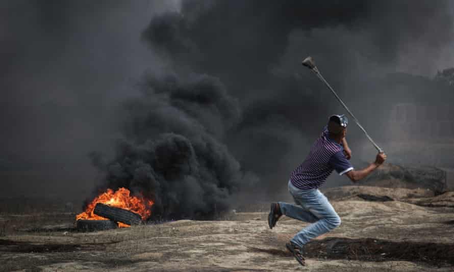 Palestinians burn tyres and throw rocks with slingshots in response to Israeli forces’ intervention during a protest in the Great March of Return.