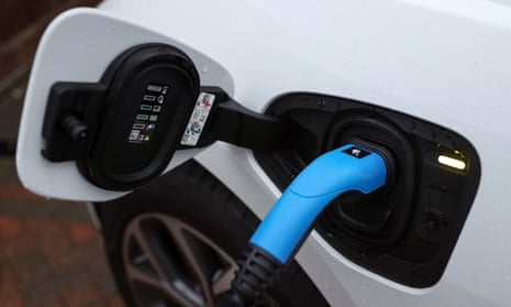 An electric charging cable connected to a Jaguar I-Pace electric car at a residential home.