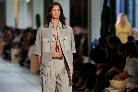 A female model in an oversized shirt over a bikini top and matching khaki trousers
