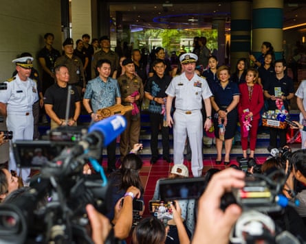 Dan Keeler, in navy uniform, stands beside local people from Pattaya in front of the hotel with a large number of television cameras and photographers in front of him