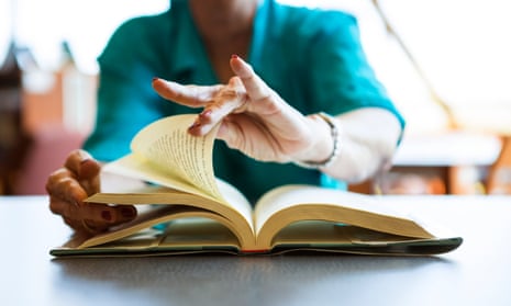 Senior woman turning pages of a book.