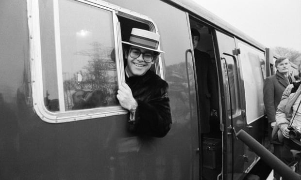 Elton John leans out of a train window