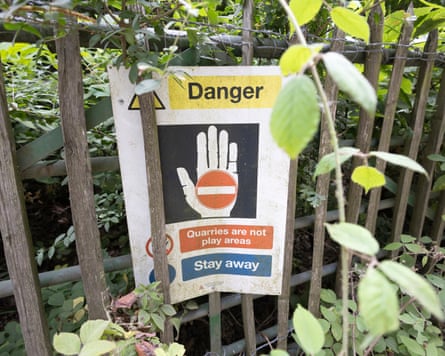 A sign on metal and wood fencing that says ‘Danger. Quarries are not play areas. Stay away’