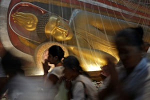 People walk past a golden Buddha statue