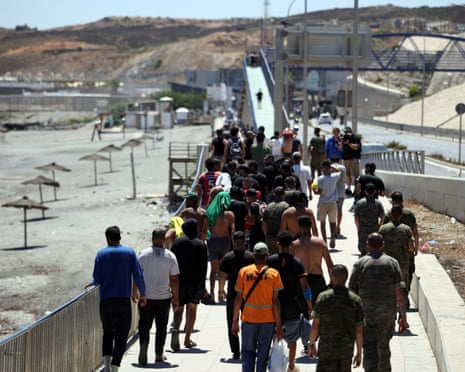 A group of migrants approach the border post to make their way back to Morocco, escorted by Spanish infantry soldiers, in the Spain’s north African enclave of Ceuta.