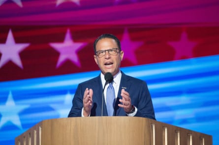 a man in suit speaking in front of a microphone on stage