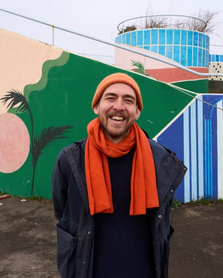 Harry Holding smiles as he poses for a picture in front of a colourful painted wall