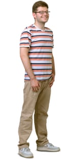 A young man with glasses and short brown hair, wearing a striped T-shirt and beige trousers